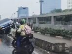 Mobil BMW Terperangkap di Atas Separator Busway Depan Gedung DPR Akibat Hujan Deras