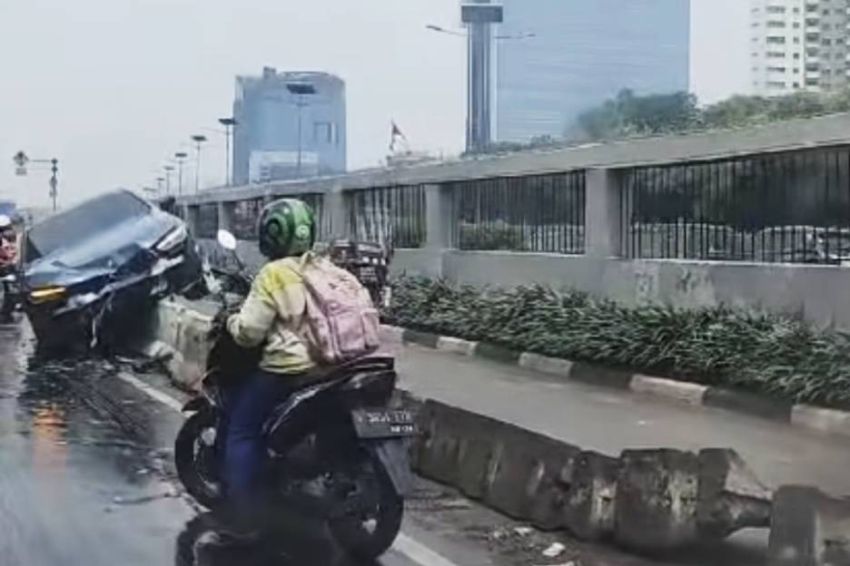 Mobil BMW Terperangkap di Atas Separator Busway Depan Gedung DPR Akibat Hujan Deras